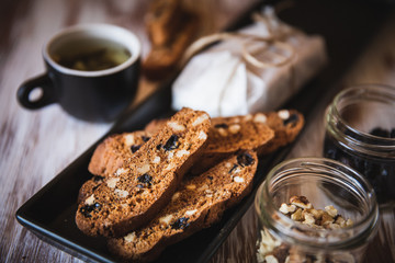 Italian biscotti cookies with walnuts and raisins, shot on a dark wooden background. Background for cooking and home baking.