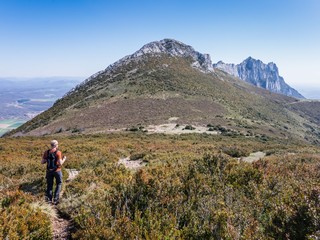 Obraz premium Male hiker descending a mountain and view over peak Recilla in the Cantabria mountain range between La Rioja and Alava, Basque Country, Spain