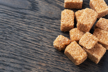 A few cubes of cane sugar on a wooden stand. Copy space.