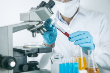 Fototapeta premium Scientist working with microscope in lab.Hold experimental Blood tube. Laboratory research concept..About experimental science such as chemical mixing or data entry to develop vaccines for everyone
