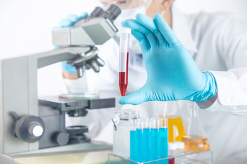 Fototapeta premium Scientist working with microscope in lab.Hold experimental Blood tube. Laboratory research concept..About experimental science such as chemical mixing or data entry to develop vaccines for everyone
