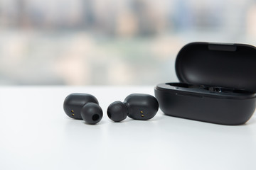 True wireless earbuds with battery case on the white table with blur city scape background