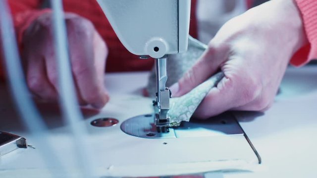 Closeup of sewing fabric on a sewing machine. Seamstress makes an element of clothing.