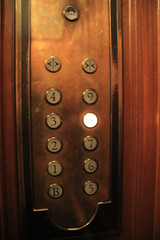 Vintage Wooden Elevator Control Panel Illuminated in Warm Light