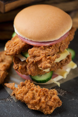 Close-up of double burger with fried chicken strips, cheese, ham and cucumber, selective focus