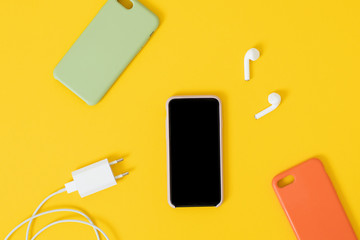 Top view of a smartphone with headphones and charge and silicone cases.