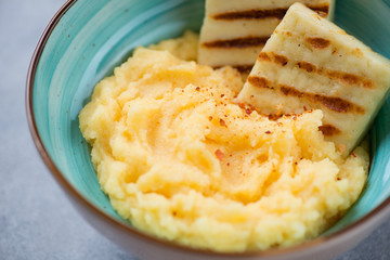 Close-up of polenta served with roasted cheese in a bowl, selective focus, studio shot