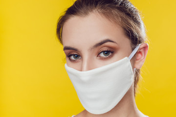 Woman wearing face protective mask on face against Coronavirus on the yellow background.