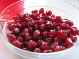 Red pomegranate grains in a glass plate close-up