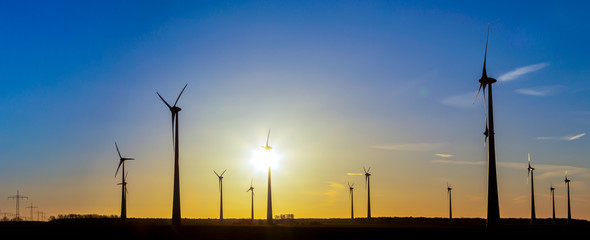 viele Windräder bei Sonnenuntergang stehen auf einem Feld und produzieren Strom