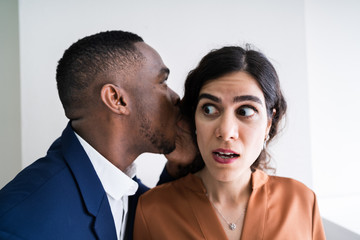 Businessman Whispering Into Female Partner's Ear