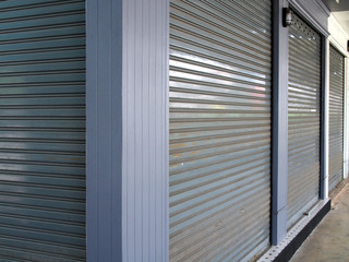 Fototapeta premium corner of store, gray metal roller shutter door of shop in flea market is closed and locked, economic downturn and epidemics caused stores closing down, out of business concept