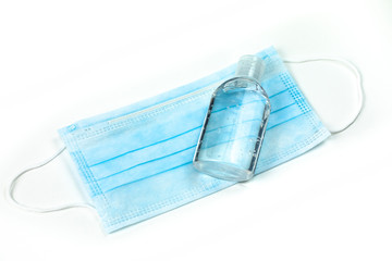 Bottle of hand sanitizer lying on medial mask isolated on white background
