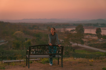 Naklejka na ściany i meble hipster girl posing smile relaxing on bench with holiday relaxing on the mountain in sunset at Northeast at Chiangkhan of Thailand