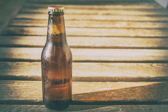 Close-up of a cold beer bottle with a wooden background