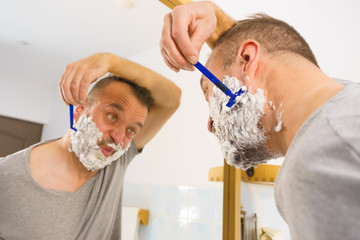 Guy shaving his beard in bathroom