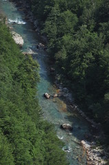 The bridge on the Tara River in Montenegro and the bridge connecting the two banks of the canyon. A stony bed of a clean river flowing through the valley along the road on a mountain slope.