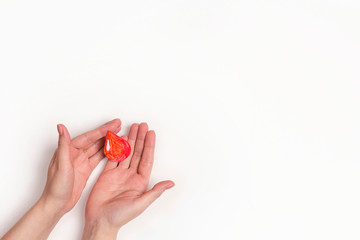 Human hands holding blood drop symbol on white background with copy space.
