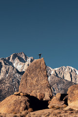 Mountain climber standing on rock peak in Eastern Sierra Nevada mountains