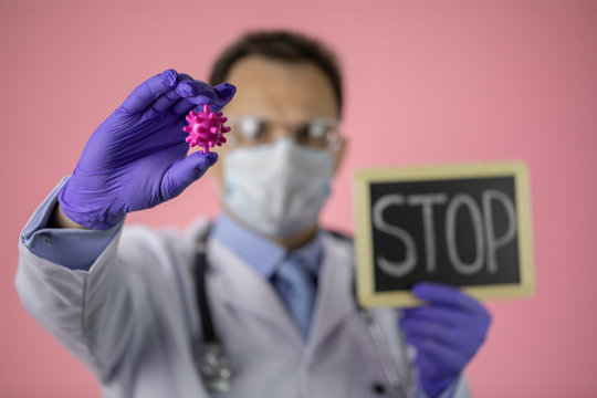 Male middle age lab technician assistant in medical uniform, protective mask and glasses holding covid-19 virus cell and stop sign. Stop spread of coronavirus global pandemic, biohazard protection