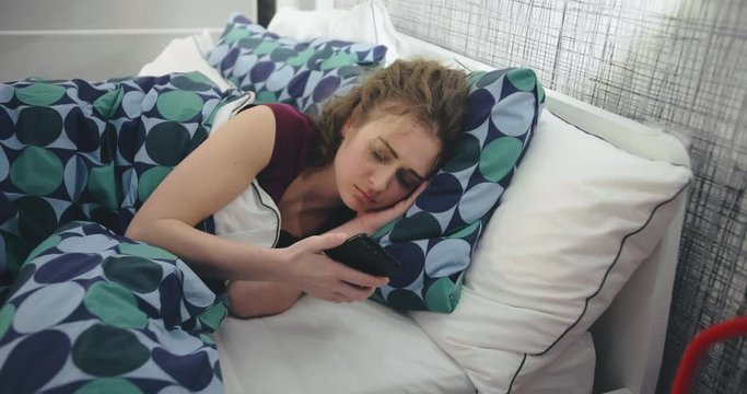 Young woman waking up because of phone ringing