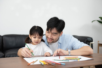 Naklejka premium A pair of young Asian father and daughter are drawing in the living room