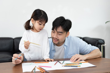 Naklejka premium A pair of young Asian father and daughter are drawing in the living room