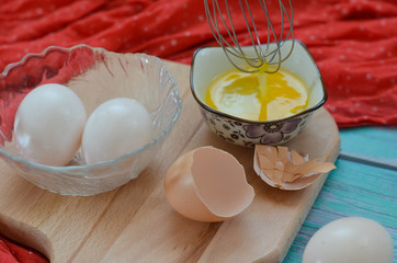 Cooking eggs, eggshells and yolks, whisk on a wooden cutting board. Easter holiday concept