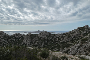 Mountains with green grass and grey rocks near the sea. Blue sky and white clouds.