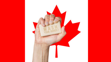 Male hand holding soap with words: Wash Your Hands, against a Canadian flag