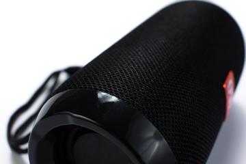 Portable Wireless Speaker Isolated on White Background. Black Sound Speaker with Ribbed Texture and Control Buttons. Vertical Position. Front View.