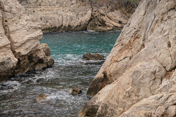 Mountains with green grass and grey rocks near the sea. Blue sky and white clouds.