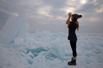 girl in winter time doing yoga at ice hummock in frozen lake Kapchagai near Almaty, Kazakhstan