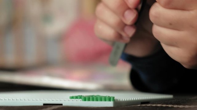 child plays with perler beads. fine motor development