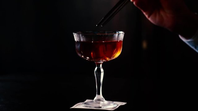 Preparazione finale di cocktail in calice di cristallo con sfondo scuro