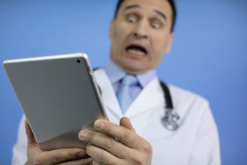 Physician looks at the tablet with the results of the patient's tests. Bad analyzes. The diagnostic doctor screams with his mouth wide open. Doctor in white medical coat with a stethoscope on his neck