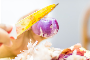 Large sizes red onion is being cut for cooking, a woman is using an old and seasoned knife 