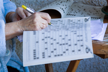Naklejka premium senior woman doing crossword puzzles or hobbies sitting
