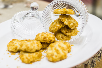 Newly baked cookies ready for a hi-tea held in a clear glass container and some were laid on a white plate