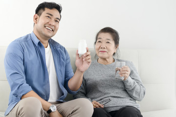 Asian man giving medicine to his mother, lifestyle concept.