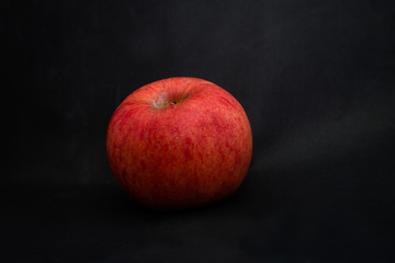 Fototapeta na wymiar Fresh red apple with droplets of water against black background with space for text