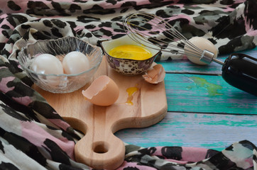 Cooking eggs, eggshells and yolks, whisk on a wooden cutting board
