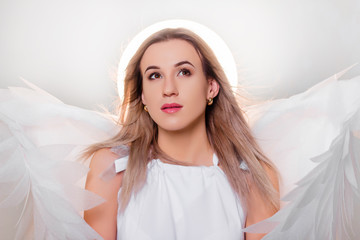 Angel in a white dress with large white wings behind his back and a halo above his head. Portrait...