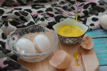 Cooking eggs, eggshells and yolks, whisk on a wooden cutting board
