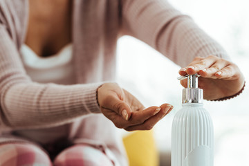 Close-up of woman using hand sanitizer at home.