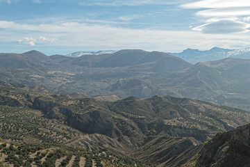 Naklejka premium Mountains with snow on the top. Green hills under the blue sky with white clouds.