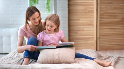 Domestic happy family mother and daughter reading book together. Shot with RED camera in 4K - Powered by Adobe