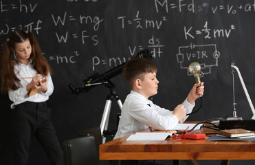 Cute little boy at physics lesson in classroom