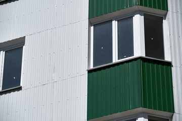 Fototapeta premium facade of a new multistory building with white and green metal siding, many Windows