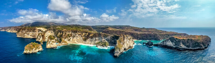 Fototapeta na wymiar Magnificent view of unique natural rocks and cliffs formation in beautiful beach known as Atuh Beach located in the east side of Nusa Penida Island, Bali, Indonesia. Aerial view.